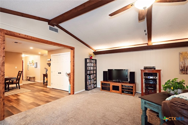 living room with hardwood / wood-style floors, ceiling fan, a textured ceiling, and vaulted ceiling with beams