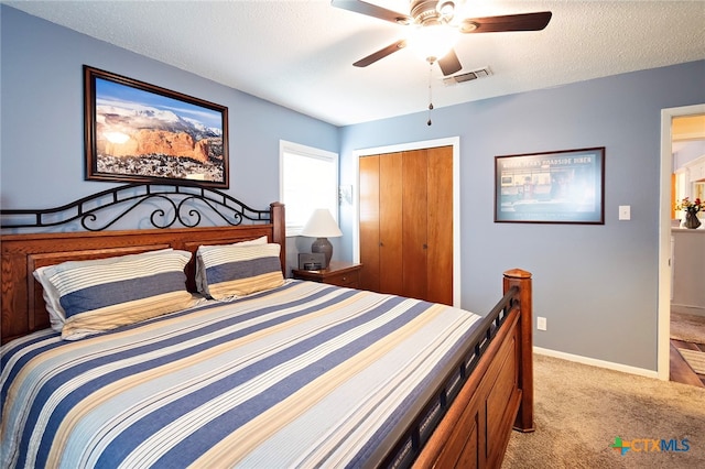 carpeted bedroom with a closet, a textured ceiling, and ceiling fan