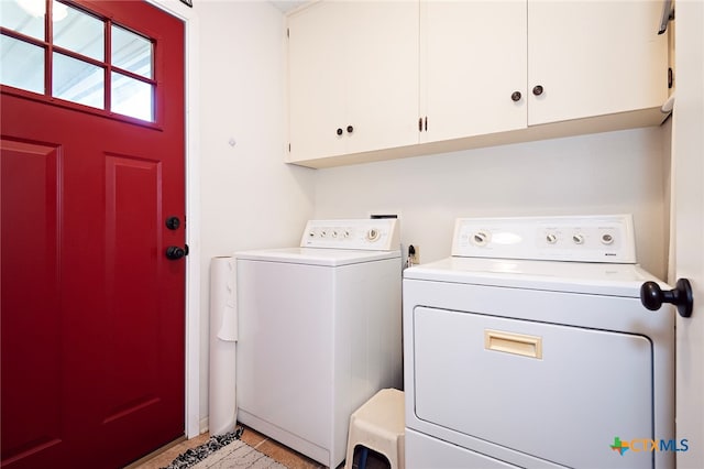 laundry area featuring washing machine and clothes dryer, cabinets, and light tile patterned floors