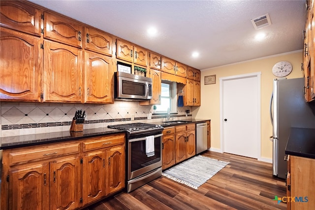 kitchen with dark hardwood / wood-style flooring, sink, tasteful backsplash, crown molding, and appliances with stainless steel finishes