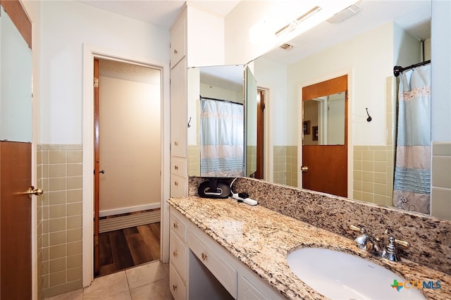 bathroom with tile walls, vanity, and tile patterned floors