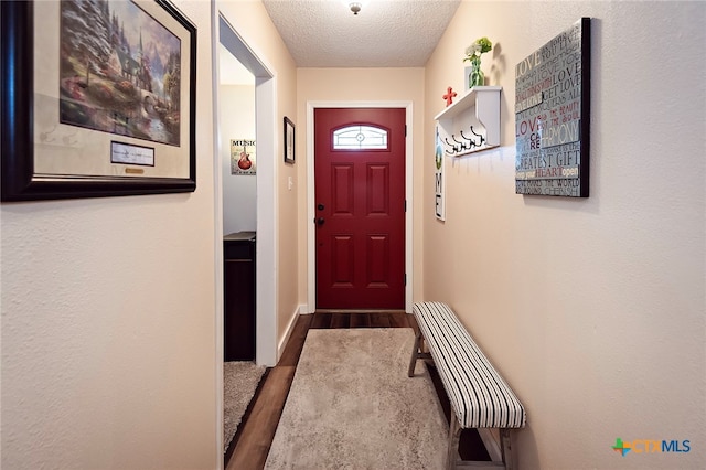 doorway with dark wood-type flooring and a textured ceiling