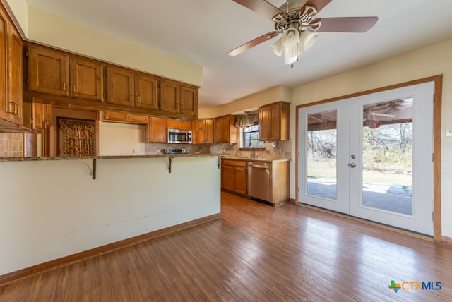 kitchen with french doors, light wood-type flooring, tasteful backsplash, a breakfast bar, and stainless steel appliances