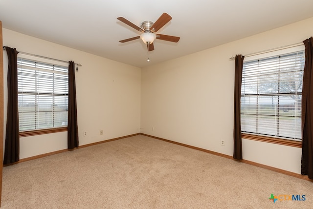 carpeted spare room featuring plenty of natural light and ceiling fan