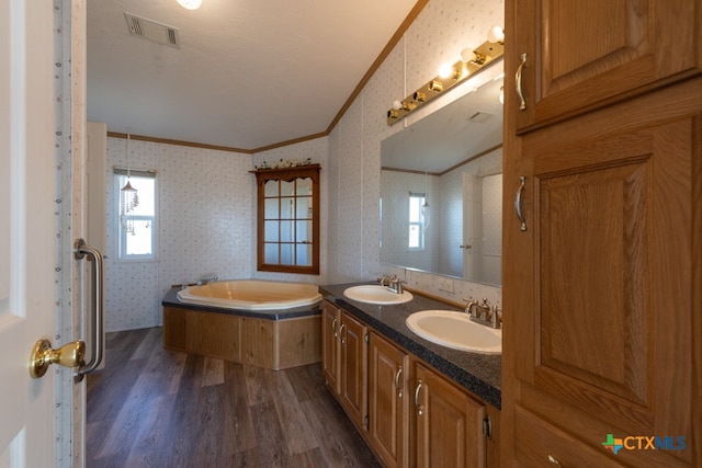 bathroom featuring a bathing tub, vanity, ornamental molding, and hardwood / wood-style flooring