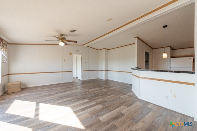 interior space featuring crown molding, ceiling fan, wood-type flooring, and lofted ceiling