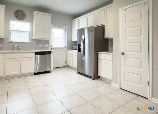 kitchen with white cabinetry, sink, stainless steel appliances, tasteful backsplash, and light tile patterned flooring