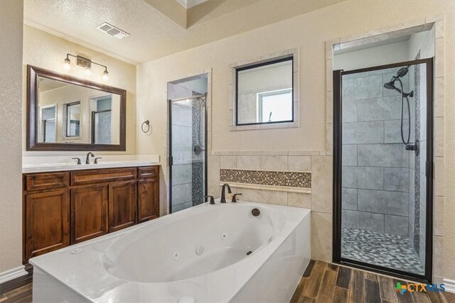 5907 Verde Dr, Killeen, TX 76549 - full bath with wood finished floors, a shower stall, a jetted tub, vanity, and a textured ceiling