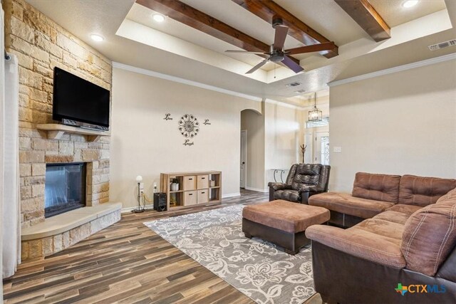 5907 Verde Dr, Killeen, TX 76549 - living room featuring arched walkways, a ceiling fan, wood finished floors, a stone fireplace, and beamed ceiling