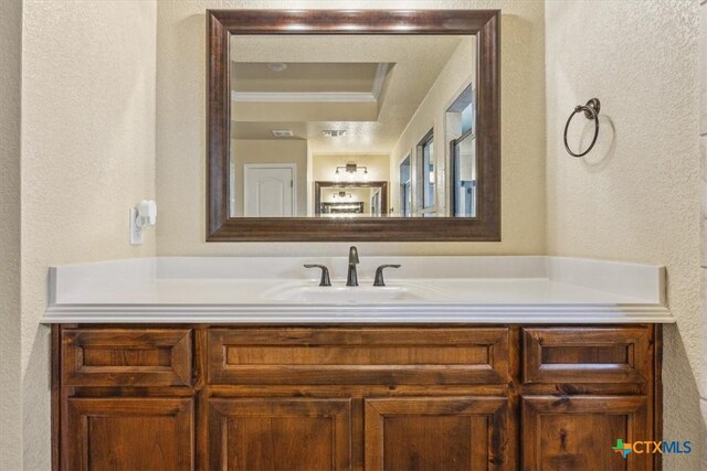 5907 Verde Dr, Killeen, TX 76549 - bathroom with a textured wall, vanity, a tray ceiling, and ornamental molding
