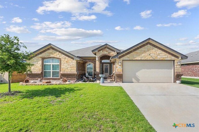 5907 Verde Dr, Killeen, TX 76549 - french country home with an attached garage, concrete driveway, stone siding, a front yard, and brick siding