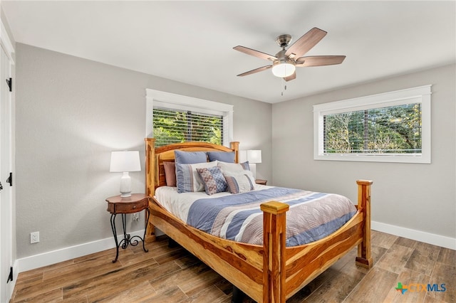bedroom featuring wood finished floors, baseboards, and multiple windows