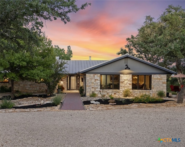 mid-century home with metal roof and stone siding