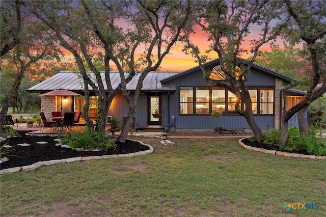 mid-century inspired home featuring a yard, a patio area, and stone siding