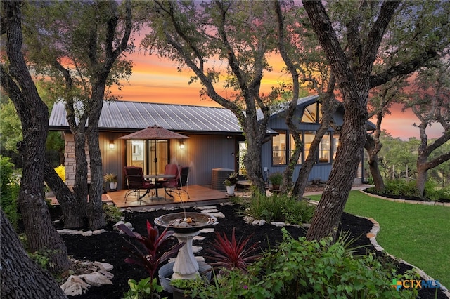 rear view of house featuring a deck, a lawn, and metal roof