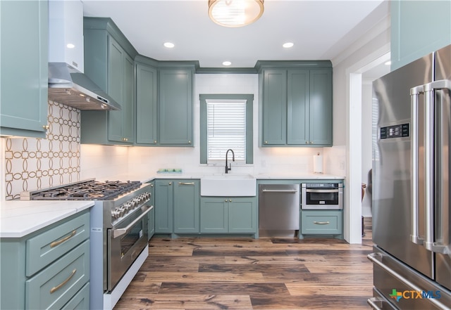 kitchen with dark hardwood / wood-style flooring, sink, tasteful backsplash, high quality appliances, and wall chimney range hood
