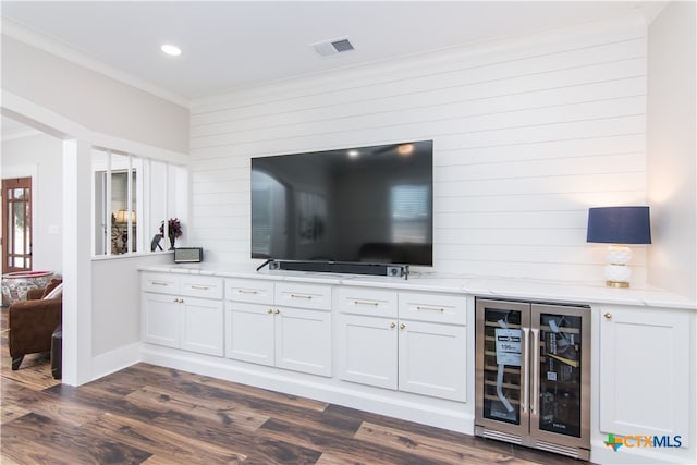 living room featuring ornamental molding, bar area, wooden walls, dark wood-type flooring, and beverage cooler