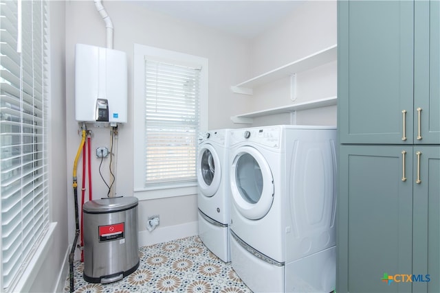 clothes washing area with light tile patterned floors, washing machine and dryer, cabinets, and tankless water heater