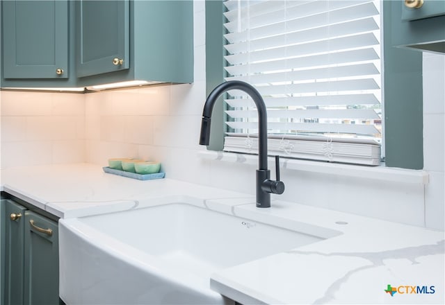 details with tasteful backsplash, light stone countertops, and sink