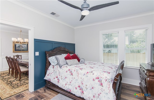 bedroom featuring dark hardwood / wood-style flooring, crown molding, and ceiling fan with notable chandelier