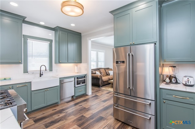 kitchen with sink, appliances with stainless steel finishes, backsplash, crown molding, and dark wood-type flooring