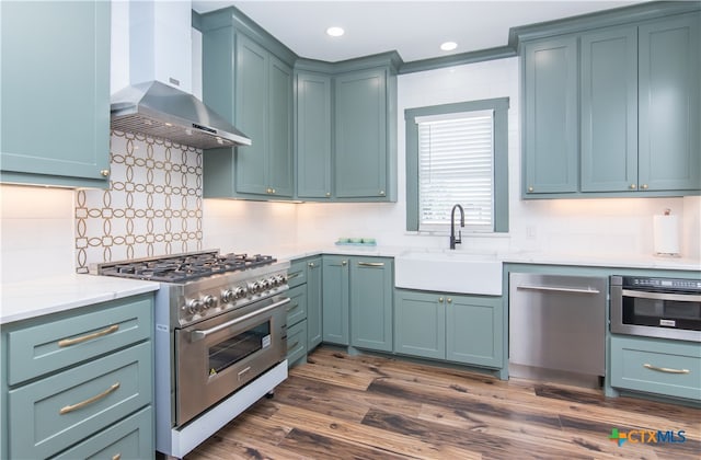 kitchen featuring wall chimney range hood, appliances with stainless steel finishes, dark hardwood / wood-style floors, and sink