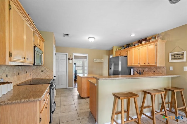 4 Longview Dr, Victoria, TX 77904 - kitchen featuring appliances with stainless steel finishes, a peninsula, tasteful backsplash, a kitchen bar, and light brown cabinets