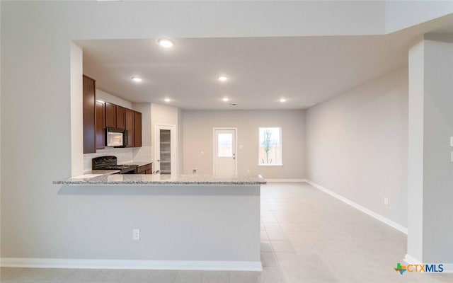 308 Angus Dr, Seguin, TX 78155 - kitchen featuring black microwave, light stone counters, recessed lighting, and stove