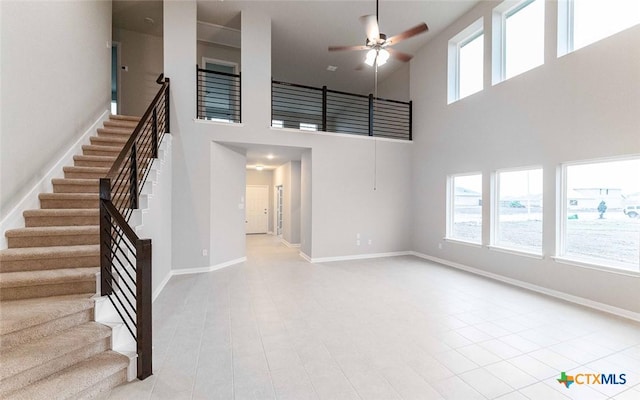 308 Angus Dr, Seguin, TX 78155 - unfurnished living room with stairway, tile patterned flooring, a towering ceiling, a ceiling fan, and baseboards