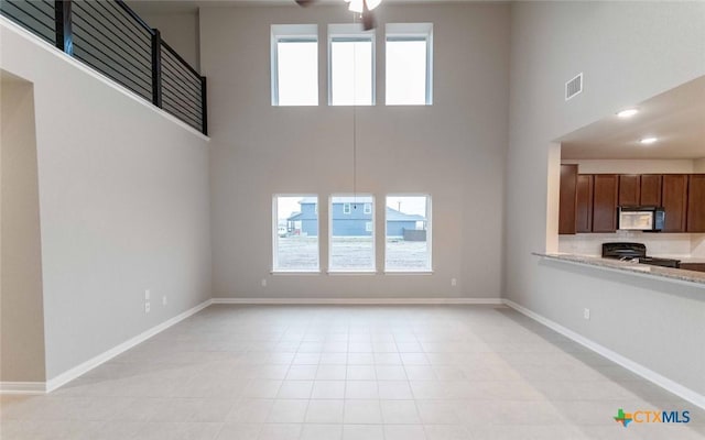 308 Angus Dr, Seguin, TX 78155 - unfurnished living room featuring visible vents, a towering ceiling, baseboards, and a ceiling fan