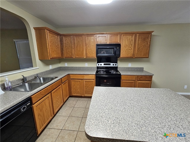 kitchen with sink, light tile patterned floors, black appliances, and a textured ceiling