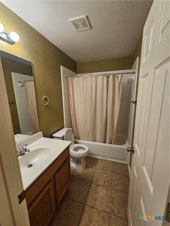 full bathroom with tile patterned flooring, vanity, toilet, and a textured ceiling