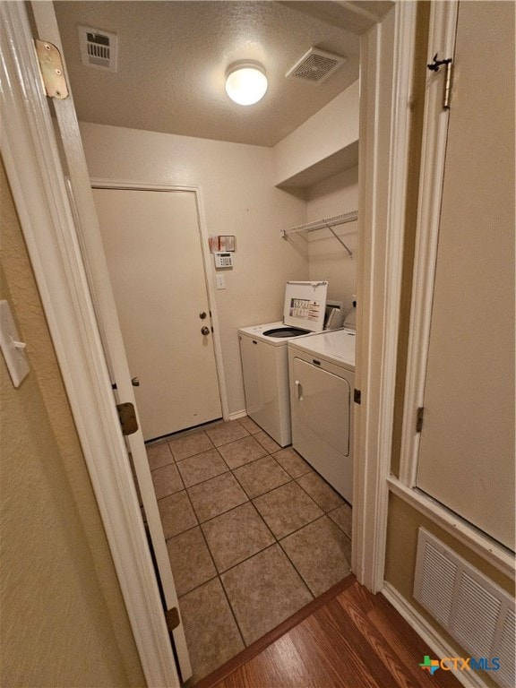 laundry area featuring washing machine and dryer, light hardwood / wood-style flooring, and a textured ceiling