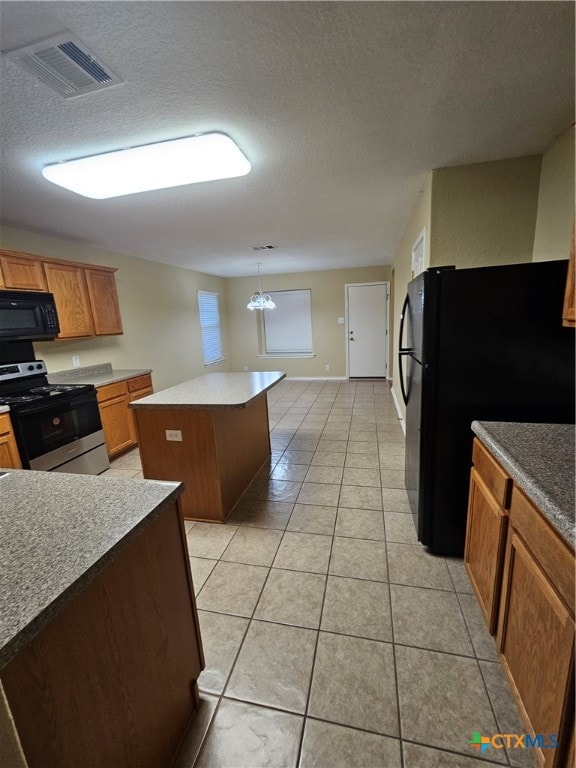 kitchen with light tile patterned floors, a kitchen island, black appliances, and a textured ceiling