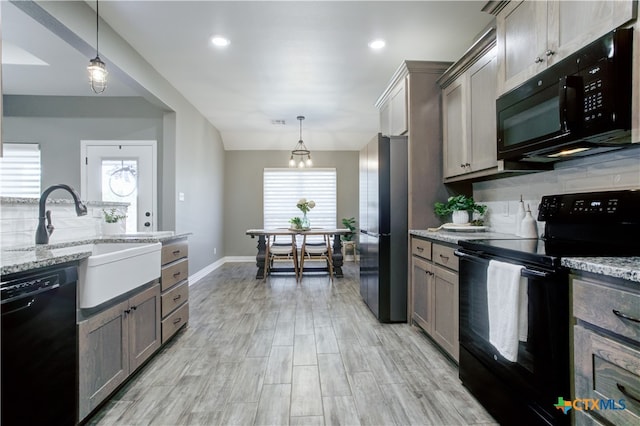 kitchen with hanging light fixtures, black appliances, and plenty of natural light