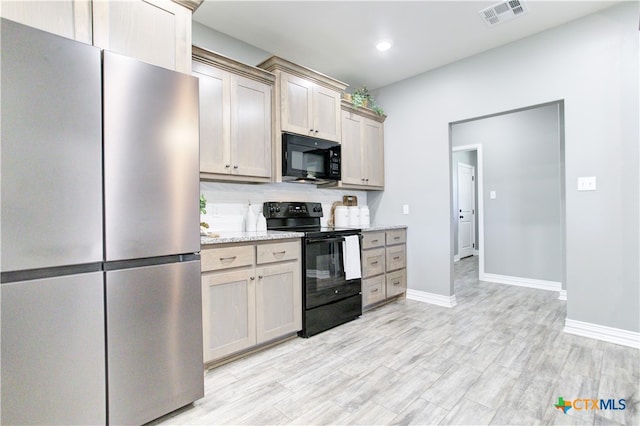 kitchen with light wood-type flooring, light stone counters, and black appliances