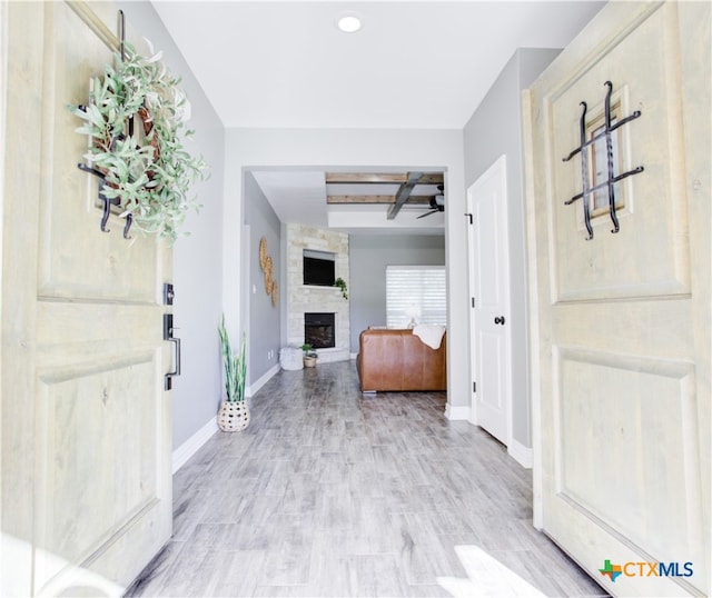 entryway with beamed ceiling, hardwood / wood-style floors, a large fireplace, and ceiling fan