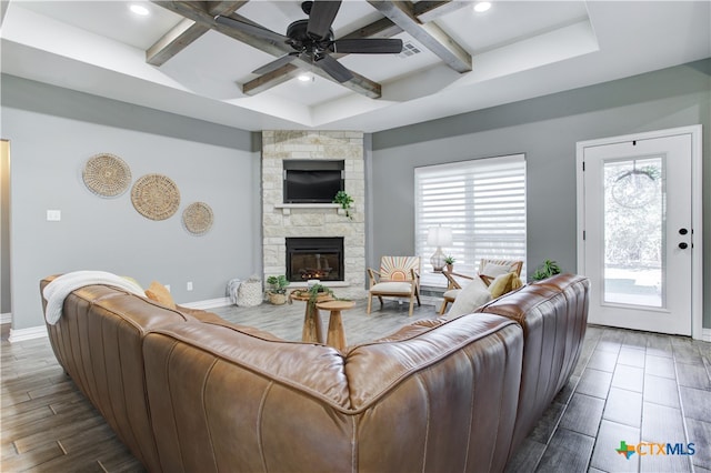 living room featuring beam ceiling, ceiling fan, a fireplace, and dark wood-type flooring