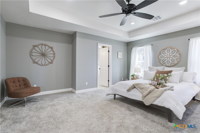 carpeted bedroom featuring ceiling fan and a raised ceiling