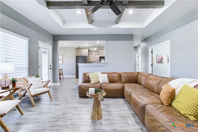 living room featuring beamed ceiling, light hardwood / wood-style floors, and ceiling fan