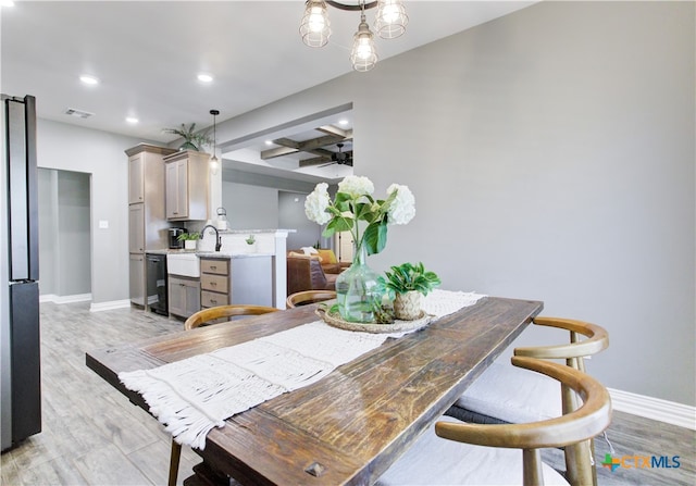 dining area featuring beam ceiling, light hardwood / wood-style floors, and sink