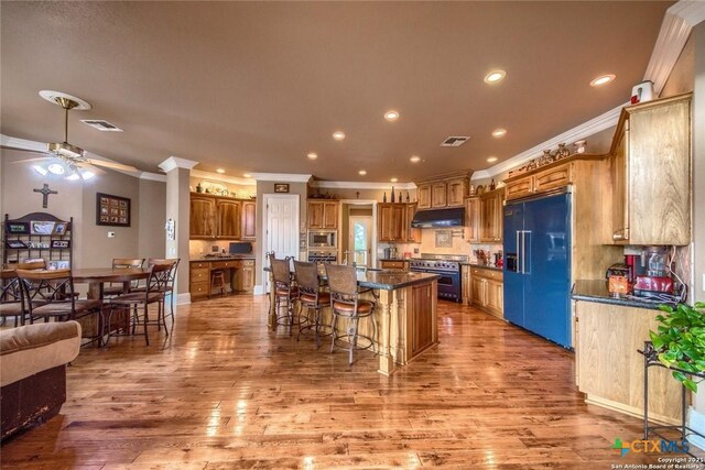 547 Powder Rdg, Luling, TX 78648 - kitchen featuring built in appliances, under cabinet range hood, crown molding, a breakfast bar area, and light wood finished floors