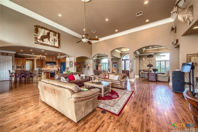 547 Powder Rdg, Luling, TX 78648 - living room featuring a ceiling fan, arched walkways, crown molding, hardwood / wood-style flooring, and a towering ceiling