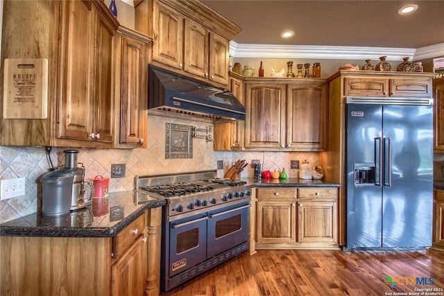 547 Powder Rdg, Luling, TX 78648 - kitchen featuring high end appliances, under cabinet range hood, brown cabinetry, dark wood-type flooring, and crown molding