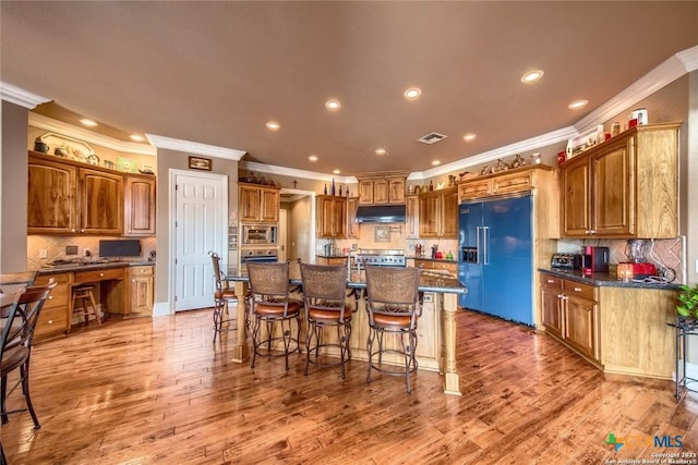 547 Powder Rdg, Luling, TX 78648 - kitchen featuring built in appliances, under cabinet range hood, ornamental molding, a kitchen bar, and a kitchen island with sink