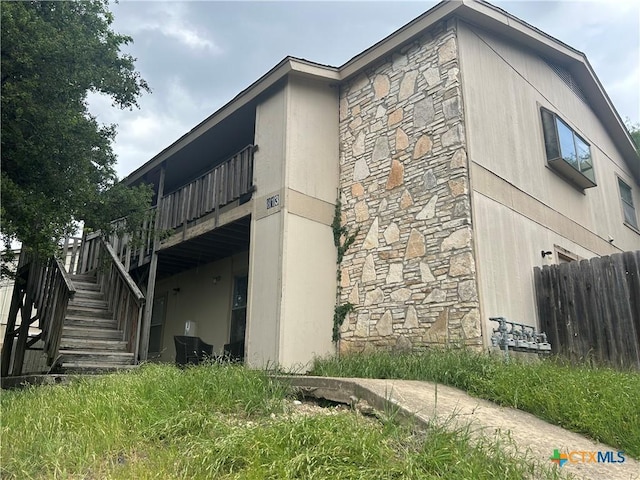 813 Bracewood Cir, San Marcos, TX 78666 - view of side of home with stucco siding, fence, stone siding, and stairs