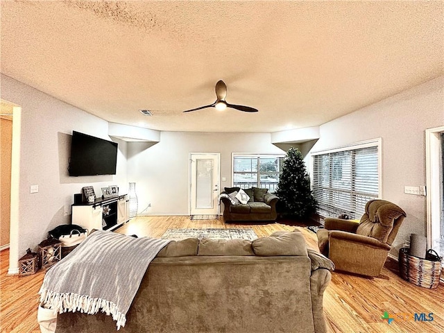 living room with hardwood / wood-style floors, a textured ceiling, and ceiling fan