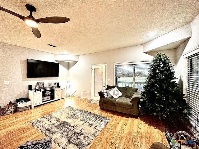 living room featuring a textured ceiling, hardwood / wood-style flooring, and ceiling fan