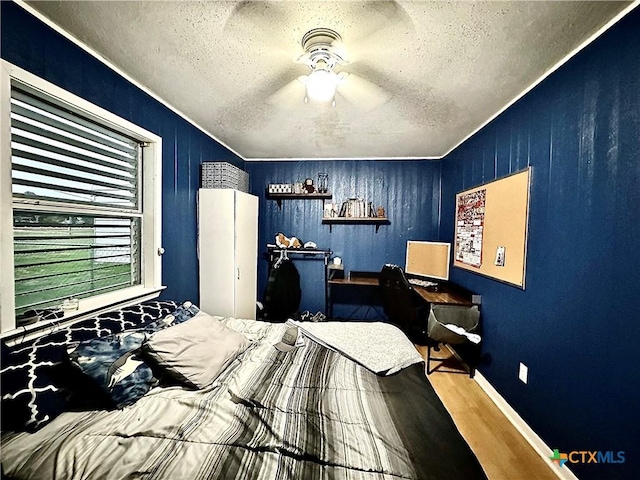 bedroom with ceiling fan, hardwood / wood-style floors, and a textured ceiling