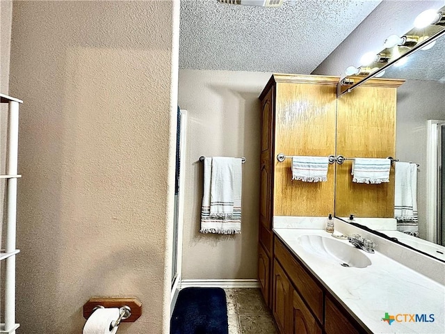 bathroom with tile patterned flooring, vanity, a shower with shower door, and a textured ceiling